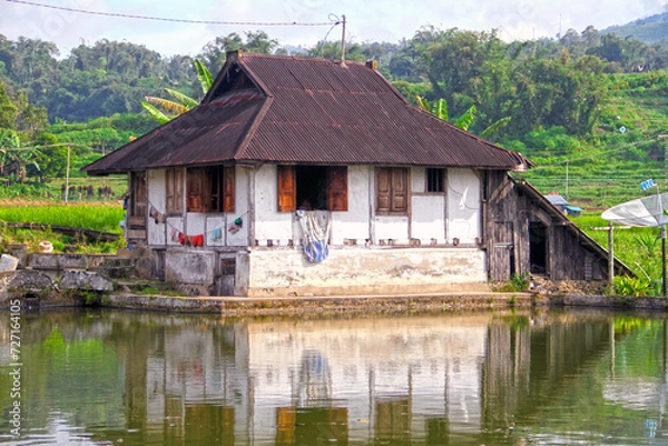 Fototapeta A small farmhouse with hanging laundry at the edge of a pond near Bukittinggi in West Sumatra, Indonesia.