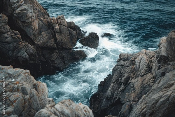 Obraz This photo captures the stunning view of the ocean from a rugged cliff, displaying the waves crashing against the rocks, A rocky coastline with crashing, foamy waves, AI Generated