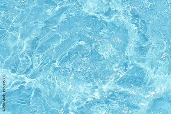 Fototapeta Water surface. Bluewater waves on the surface ripples blurred. Defocus blurred transparent blue colored clear calm water surface texture with splash and bubbles. Water waves with shining pattern.