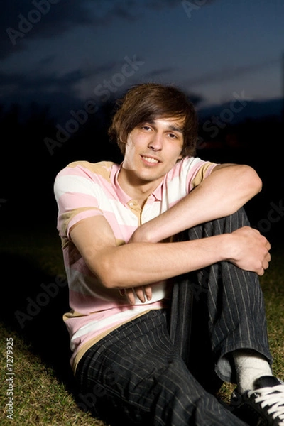 Obraz Young man siting on grass in night