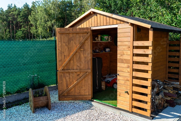 Obraz A wooden garden shed standing on a concrete foundation in a garden.