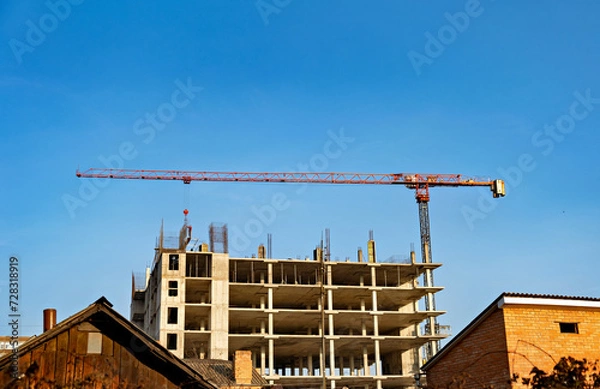 Fototapeta Building under construction with crane on top of it and building under construction in the background.
