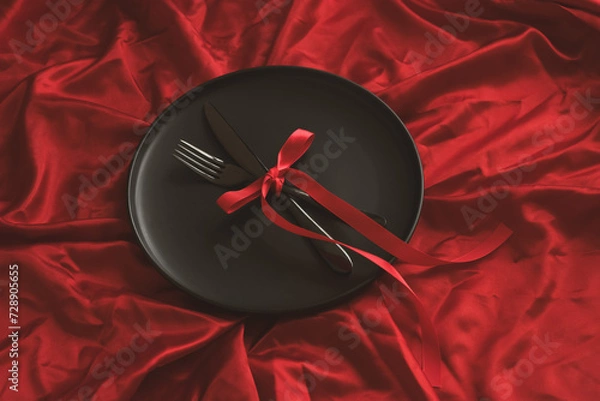 Fototapeta There is a plate with cutlery on a red background. Holiday concept