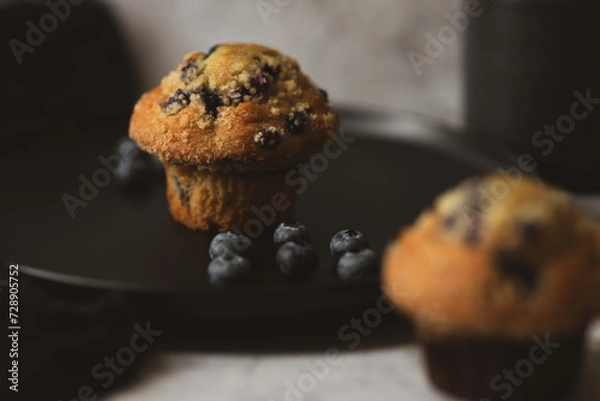 Fototapeta There is a cupcake and blueberries on a black plate. Breakfast concept