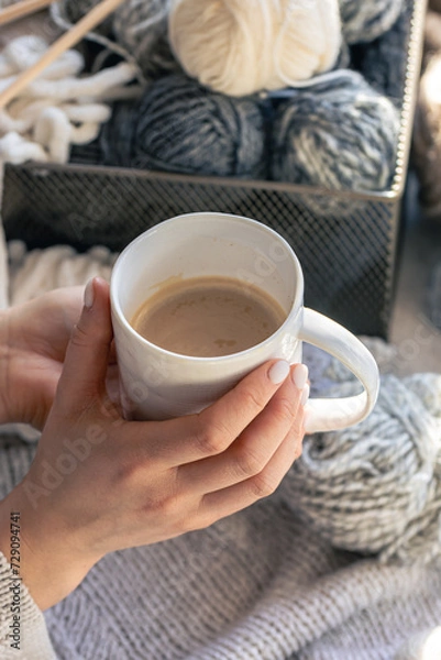 Obraz A cup of coffee in female hands and a thread of yarn.
