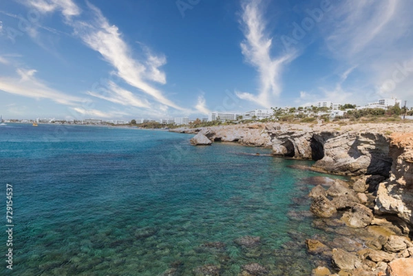 Fototapeta Vacation resort of Ayia Napa. A paradise for vacationers. A sunny day with a blue sky and white clouds. Panoramic view of the hotels, the blue lagoon and the coastline with rocks and caves. Cyprus. 