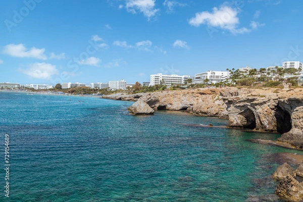 Fototapeta Vacation resort of Ayia Napa. A paradise for vacationers. A sunny day with a blue sky and white clouds. Panoramic view of the hotels, the blue lagoon and the coastline with rocks and caves. Cyprus. 