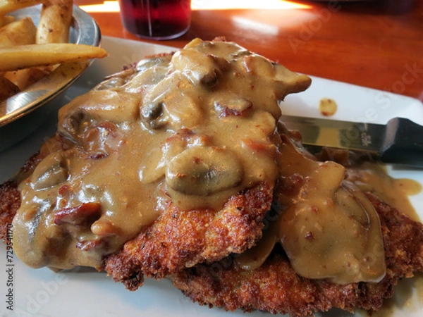 Obraz Pork schnitzel with mushroom gravy, served with French fries