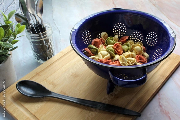 Obraz Tri-colored fresh tortellini pasta in a colander, ready to cook