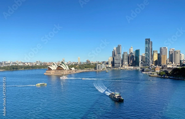 Fototapeta View of Sydney Harbour, Australia. Sydney Opera House and iconic buildings on the island. Panorama of the city's coastline from the ocean with boats and ferries on the water.