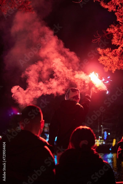 Fototapeta Man holding red torch with smoke to celebrate