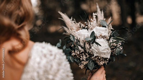 Obraz wedding bouquet in boho style collected from wild flowers, the bride holds a bouquet in her hand, in nature, white dress, live plants, a composition of dried flowers