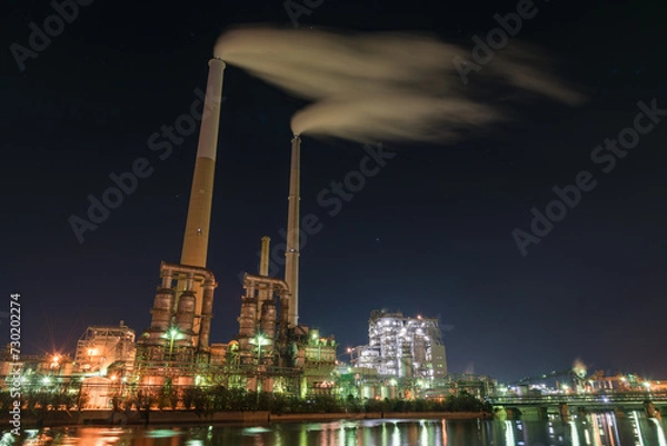 Obraz 闇夜に浮かぶ光り輝く工場と煙たなびく２本の煙突