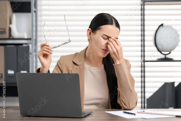 Obraz Woman suffering from headache at workplace in office