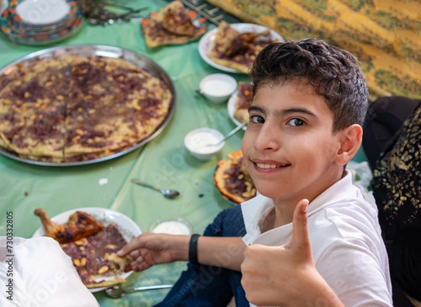 Fototapeta Portrait Of boy making vector gesture or two number with hand while eating with family and smile