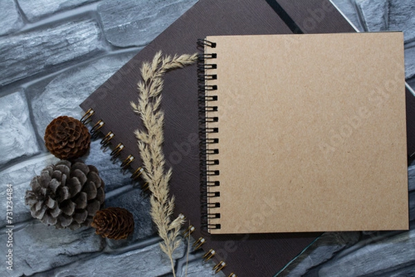 Obraz Notebooks, cones, stones on a wooden table top view. Workspace, artist's creative workshop. Cozy home interior in brown tones.
