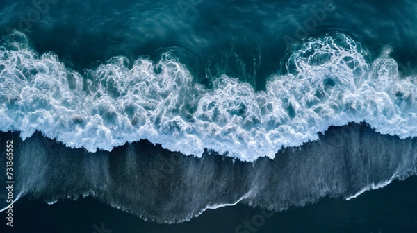 Fototapeta Aerial drone view or top view perspective photography of a beautiful transparent clear sea or ocean waves and foam splashing on the dark navvy blue or gray sand beach 