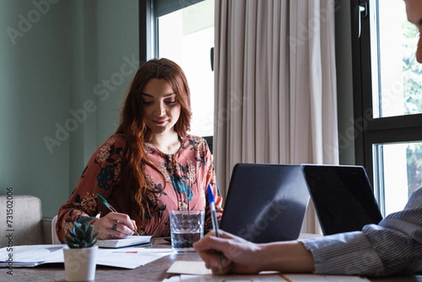 Fototapeta Colleagues at desk in office working on laptop