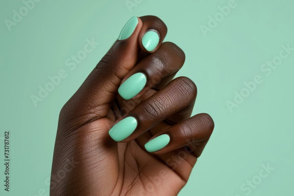 Fototapeta African American womans hand with long nails and turquoise color manicure against green background