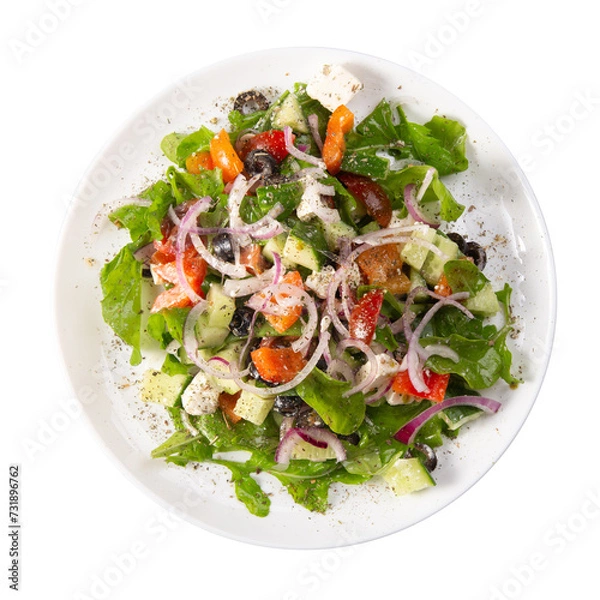 Obraz Traditional greek salad with fresh ingredients, feta cheese, olives, red tomatoes, cucumbers and greens in white plate, isolated on white background. Top view, close up, copy space.
