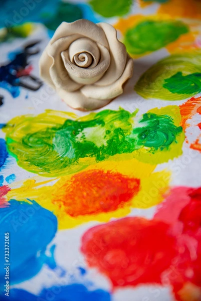 Obraz White rose on the background of a multicolored palette of paints