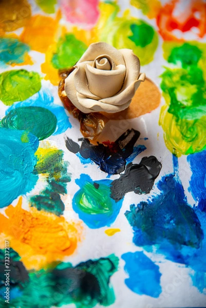 Obraz White rose on the background of a multicolored palette of paints