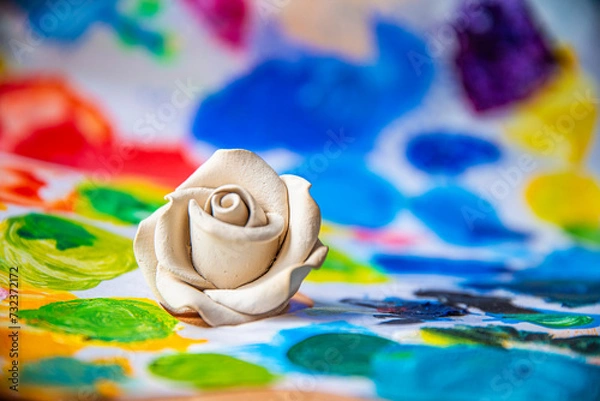 Obraz White rose on the background of a multicolored palette of paints