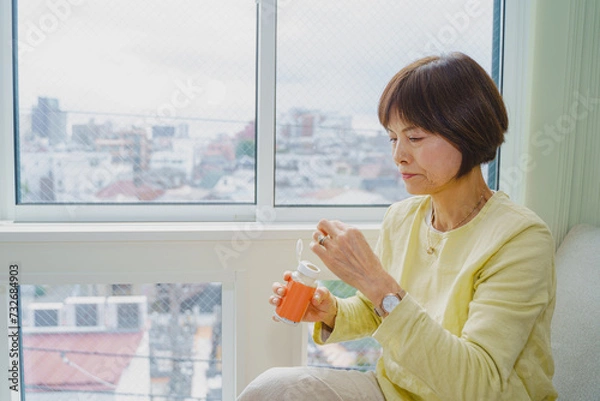 Fototapeta 薬をボトルから取り出すシニア女性