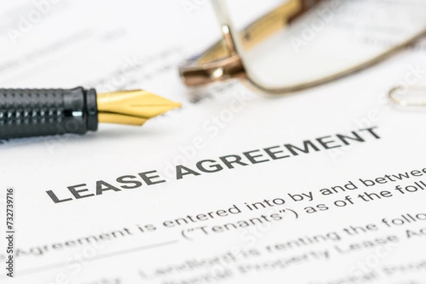 Fototapeta Business legal document concept : Pen and glasses on a lease agreement form. Lease agreement is a contract between a lessor and a lessee that allow lessee rights to use of a property owned by lessor.