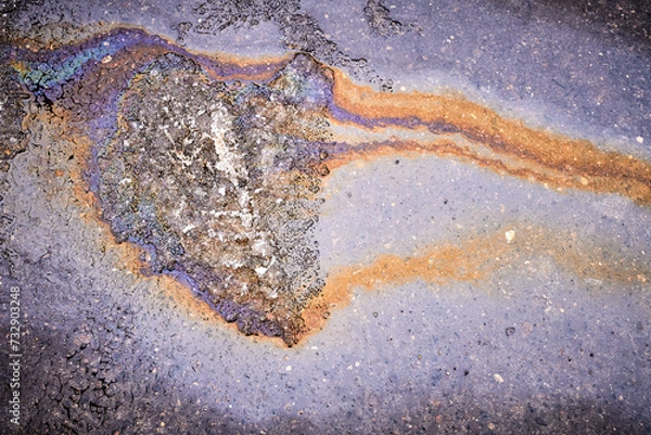 Fototapeta A bright spot of oil or gasoline splash on the asphalt after the snow melts