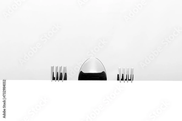 Obraz Forks and spoons are discussing at the table. Hiding behind the table, they watch what is happening on the table. 