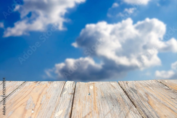 Fototapeta photo of a wooden board with a blue sky and clouds in the background