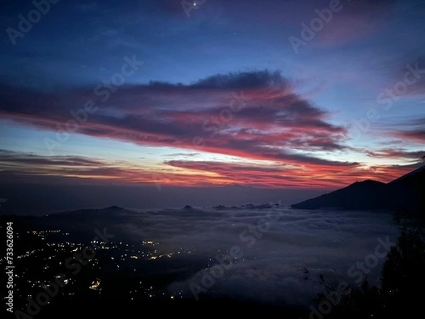 Fototapeta View of a town and volcanic mountain during sunrise