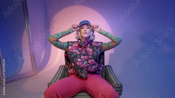 Fototapeta Cool hipster student woman wearing stylish outfit looking at camera and correcting her hat