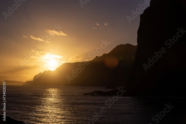 Fototapeta Sunrise from behind of cliffs - Guindaste viewpoint - Madeira, Portugal