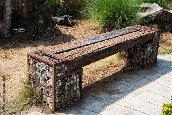 Obraz Wooden park benches are made from logs and stones.