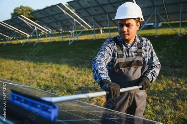 Obraz Indian handyman cleaning solar panels form dust and dirt