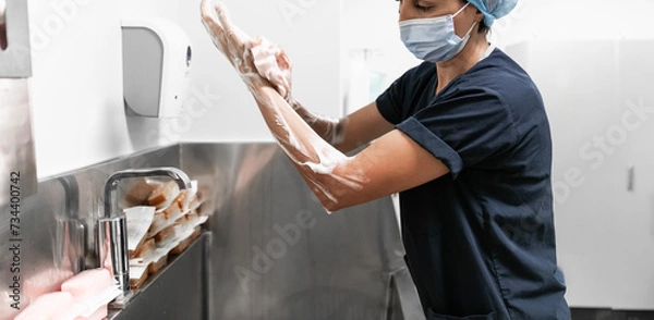 Fototapeta Surgeon having her hands surgically washed. A Caucasian doctor dressed in his right-hand profile with her hands full of foam and dressed in her surgical uniform. 