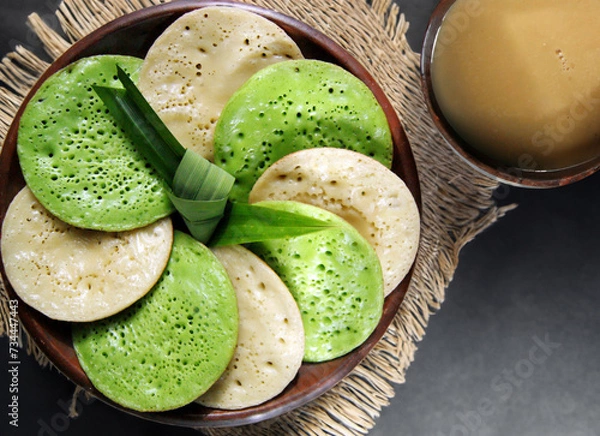 Fototapeta Serabi Pandan, Javanese Asian coconut-milk and pandanus pancakes with syrup of coconut milk and palm sugar. Served in traditional Java Indonesia Asia culture style