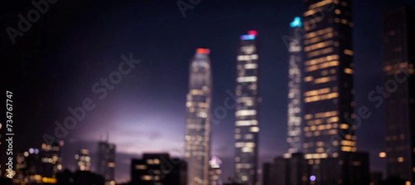 Fototapeta Abstract night lights of a modern futuristic cityscape. Defocused image, view of a dark modern urban skyline in the evening glow with many tall buildings, towers, skyscrapers with glowing windows.