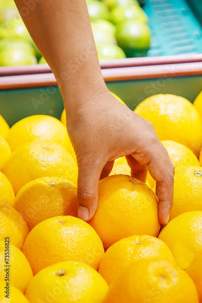 Obraz Hand holding orange in department store