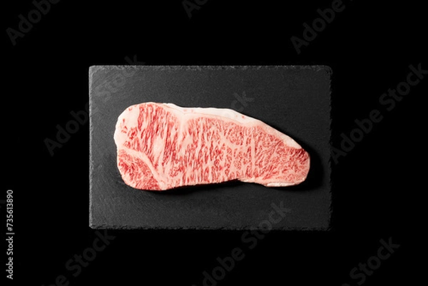 Fototapeta Fresh raw beef steak placed on a stone plate against a black background. Wagyu beef steak.