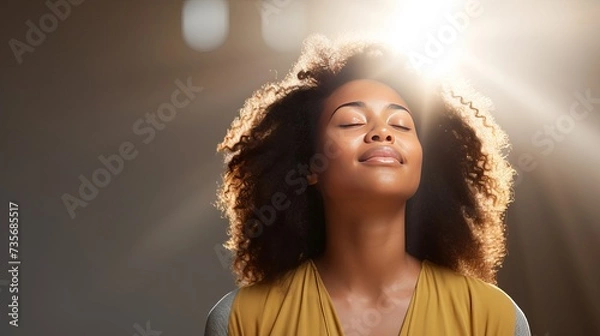 Fototapeta Meditation concept. Beautiful young black woman stands in meditative pose, enjoys peaceful atmosphere, holds hands in praying gesture, isolated over white background, has sense of inner peace