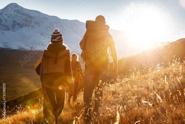 Obraz Group of hikers tourists with backpacks walks in sunset mountains. Active lifestyle concept