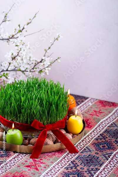 Fototapeta Beautiful Novruz tray on rug with semeni - wheat grass with red ribbon, festive candles on national Azerbaijani carpet table cloth with blooming branch,Spring equinox and new year celebration in Baku.