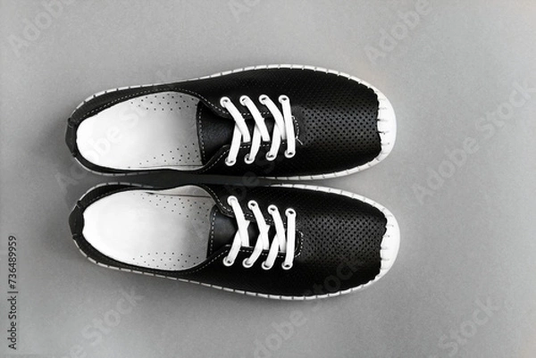 Obraz Stylish black leather sneakers on a gray background, close-up.