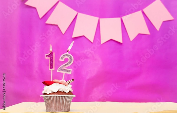 Obraz Background date of birth with number  12. Pink background with a cake and burning candles, save space, happy birthday anniversary for a girl. Holiday pudding muffin.