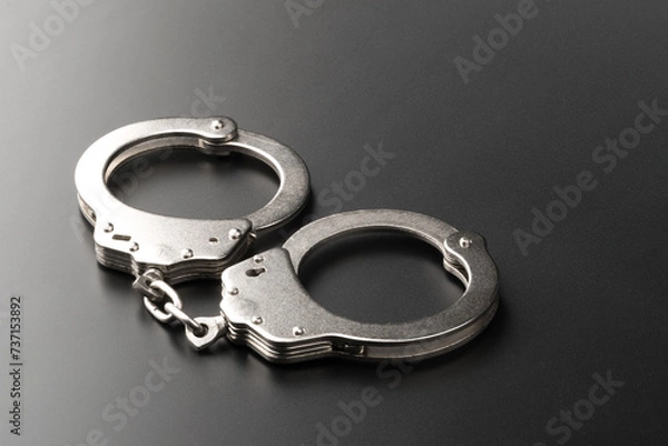Fototapeta Police handcuffs on dark background with copy space