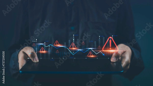 Fototapeta Business economy crisis and investment risks. Tablet show virtual stock graph data fall with alert warning sign for caution finance investing economic recession situation warning.