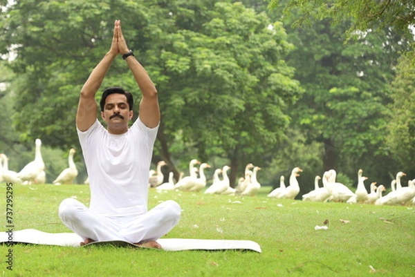 Obraz Happy Indian man doing yoga early morning in a tranquil environment surrounded with lush green serene atmosphere. high concentration level. 